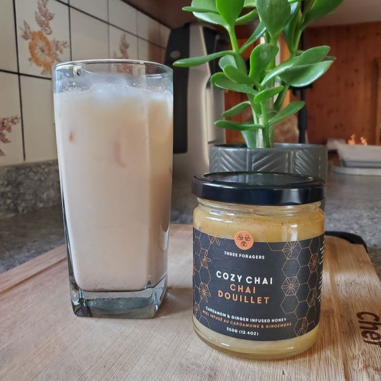 Honey iced chai latte next to a jar of Cozy Chai honey