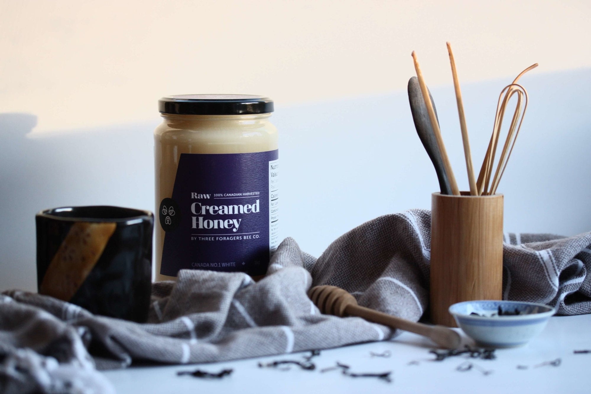 Creamed Honey between a cup and a utensil holder